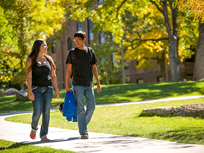Two students walk on campus in fall.