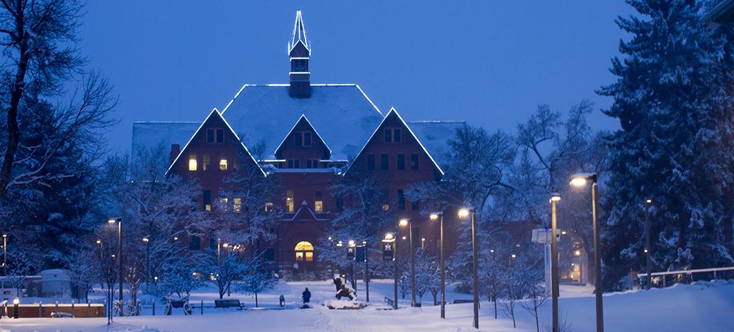 Montana Hall in winter during twilight.