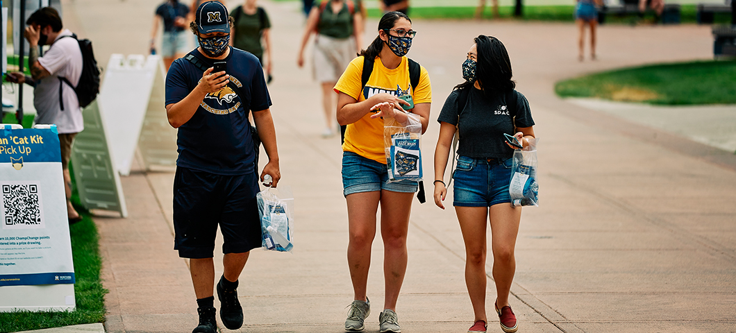 Students wearing masks while walking down Centennial Mall