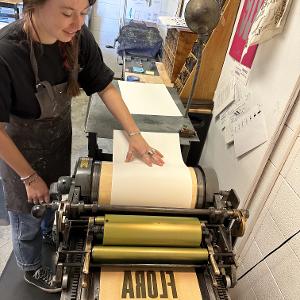 A student uses the Vandercook press to print a laser-cut form. 