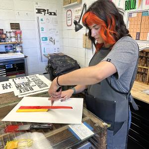 A student pulls ink after mixing two custom colors. 