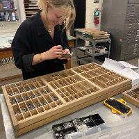 A participant uses the california case to set metal type. 