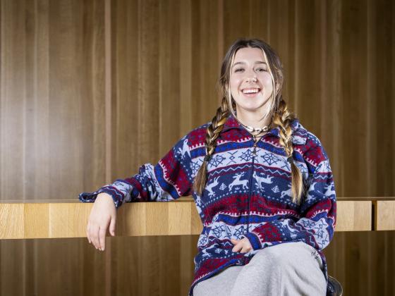 A portrait of Ashlin Ivester sitting in front of a wood wall | MSU Photo by Marcus "Doc" Cravens