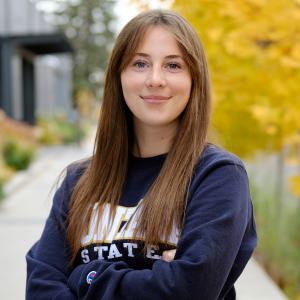 Cadee Hess standing in front of trees with yellow leaves wearing a Montana State sweatshirt.