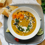 A soup in a bowl with crusty bread on the side.