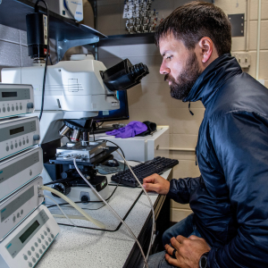 Kevin Hammonds sitting at a microscope in a lab.