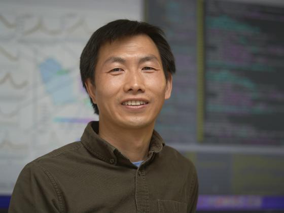 A man stands in front of a screen displaying computer code and data images |  MSU Photo by Colter Peterson