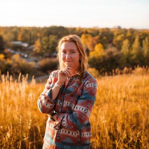 A woman in a flannel shirt in front of a golden field