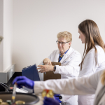 Three people in white lab jackets working with laboratory equipment