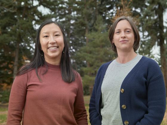 Two women stand together  in front of a grove of coniferous trees | MSU Photo by Colter Peterson