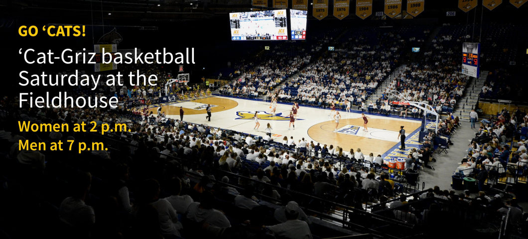 Alt text: A packed basketball arena shows fans dressed in white watching a game at Montana State University's Brick Breeden Fieldhouse. Players from MSU and the University of Montana compete on the court, with banners hanging from the rafters. Large w | MSU Image