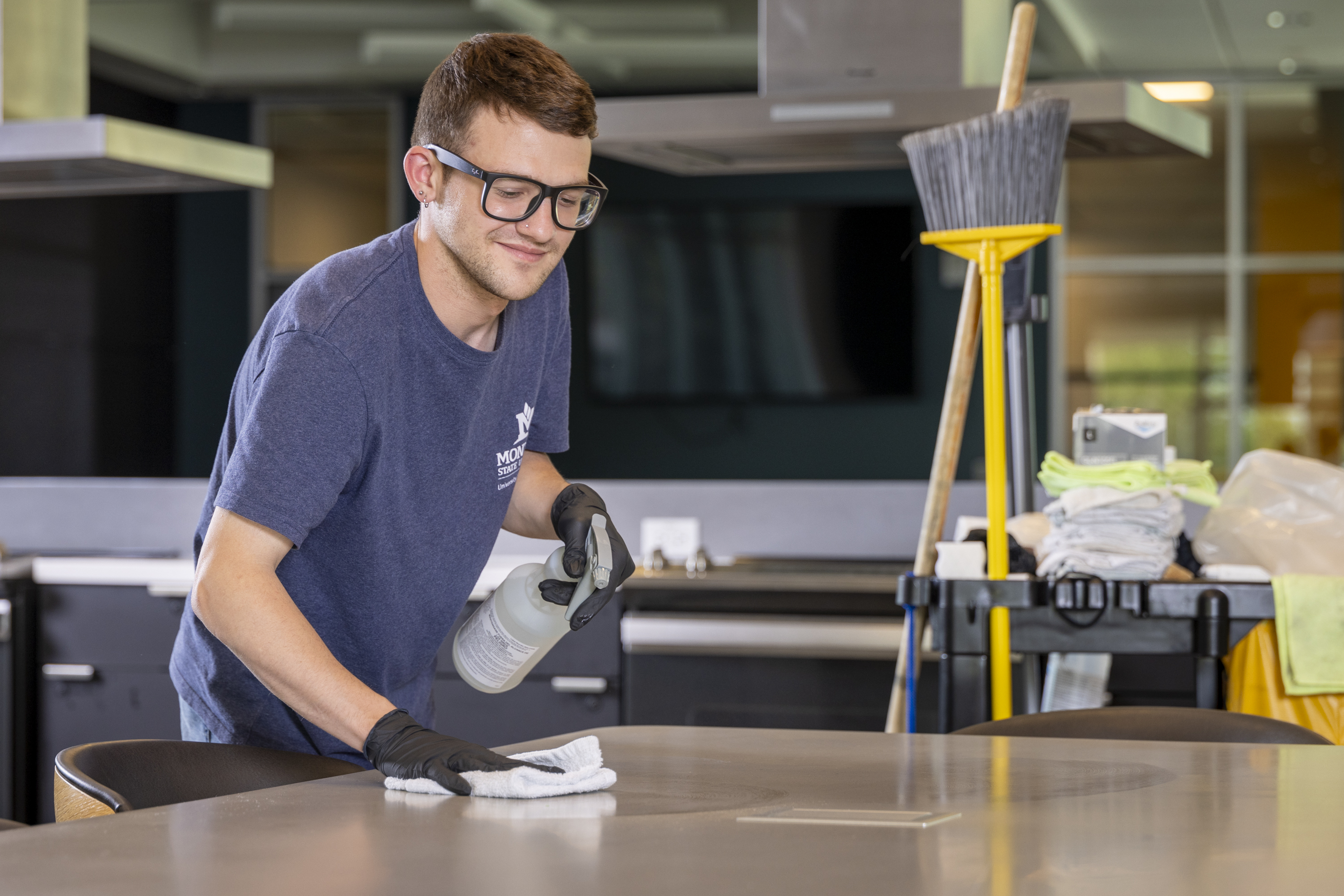 custodian staff member cleaning a table