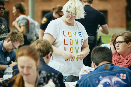 A student wearing a shirt printed with the word "love" three times takes part in an LGBTQ pride event on campus.