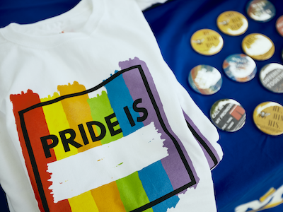 Stock image of an LGBTQ pride t-shirt and t-shirt buttons.