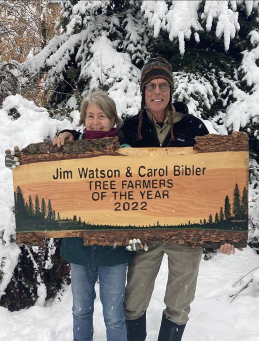 Jim Watson and Carol Bibler holding their Tree Farmers of the Year sign amidst snow and chilly weather.