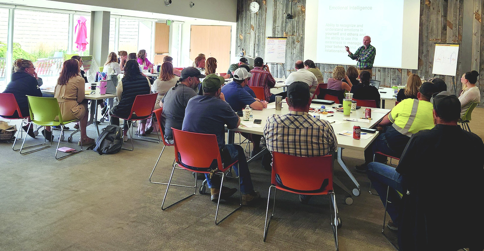 People sit in a classroom environment and listen to a person present.