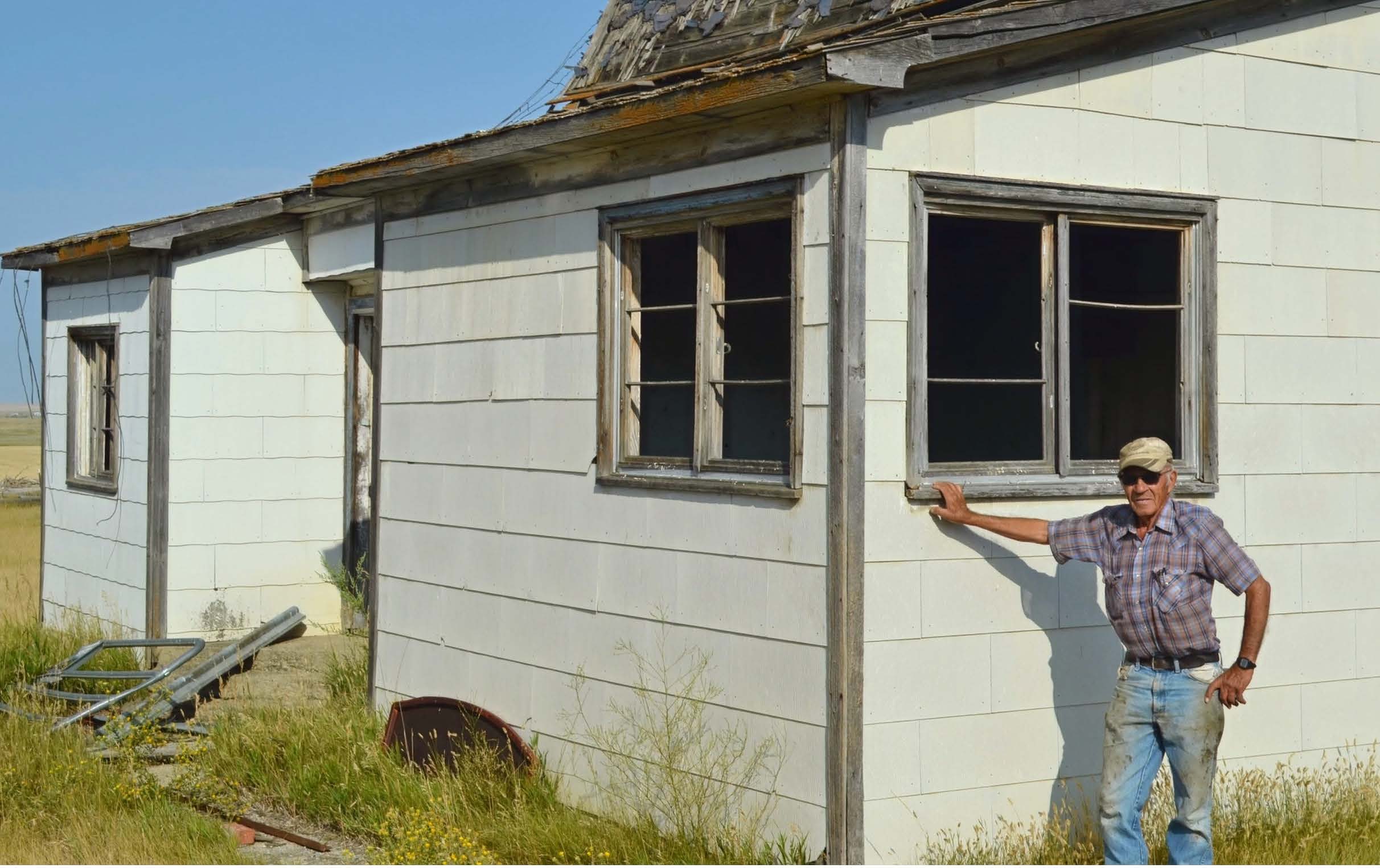 man standing in front of an old abandoned house.