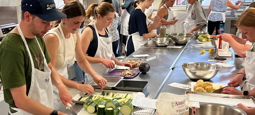 MDI interns prepping food around a large kitchen table during Culinary Medicine session