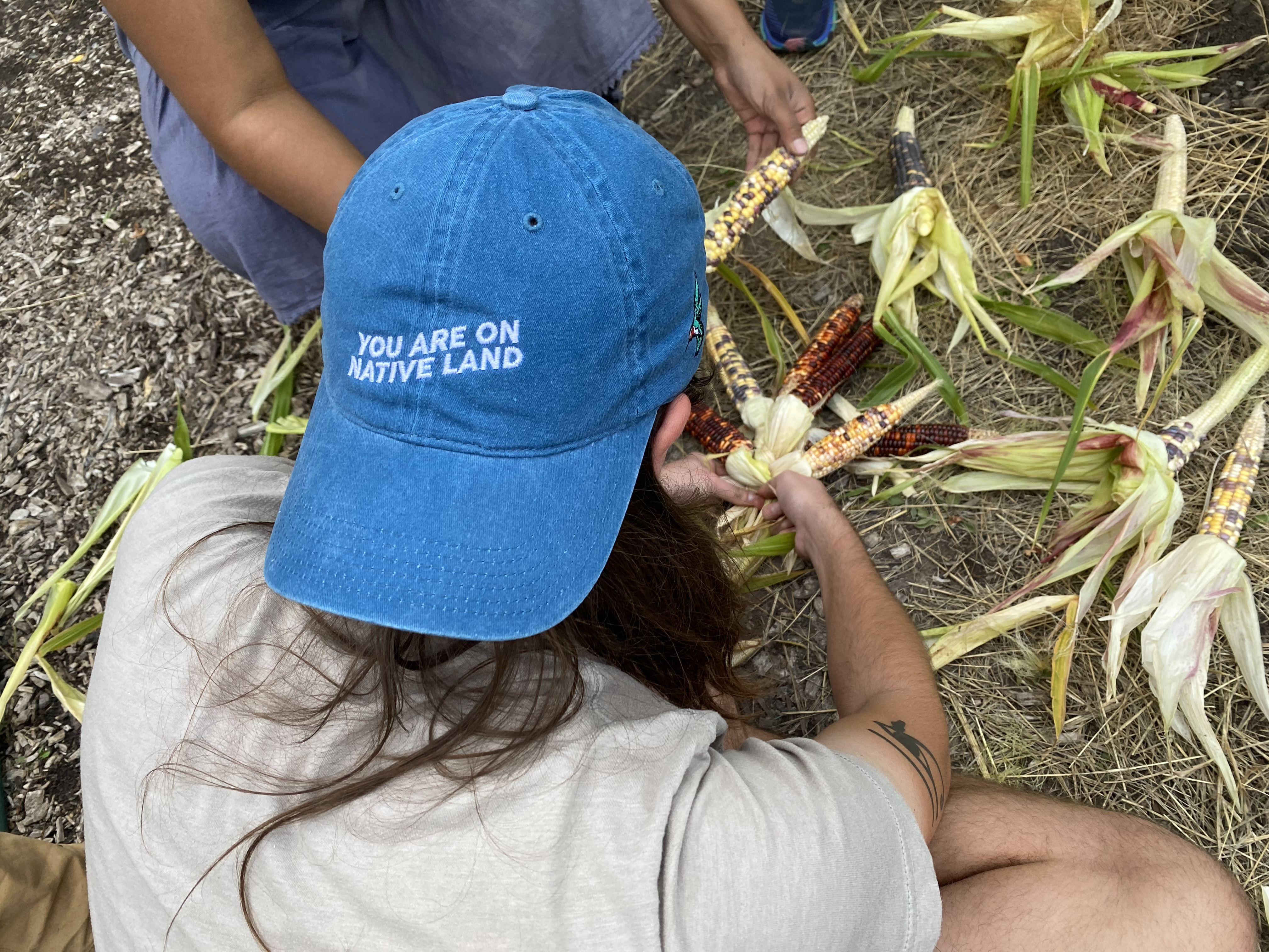 Buffalo Nations fellow braids corn with a powerful message on his hat