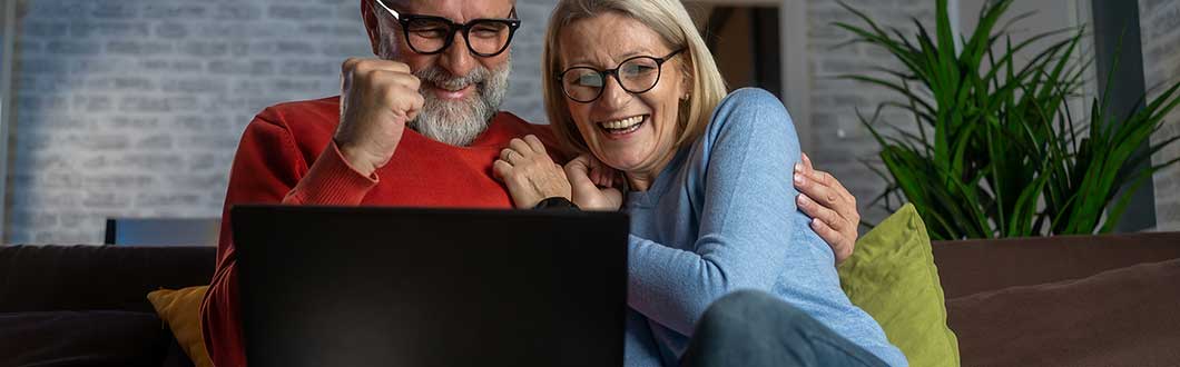 Man fist pumping and embracing his partner in front of a computer